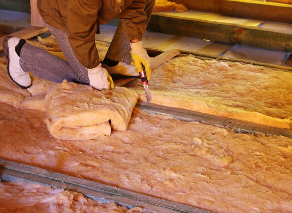 worker adding insulation to a home